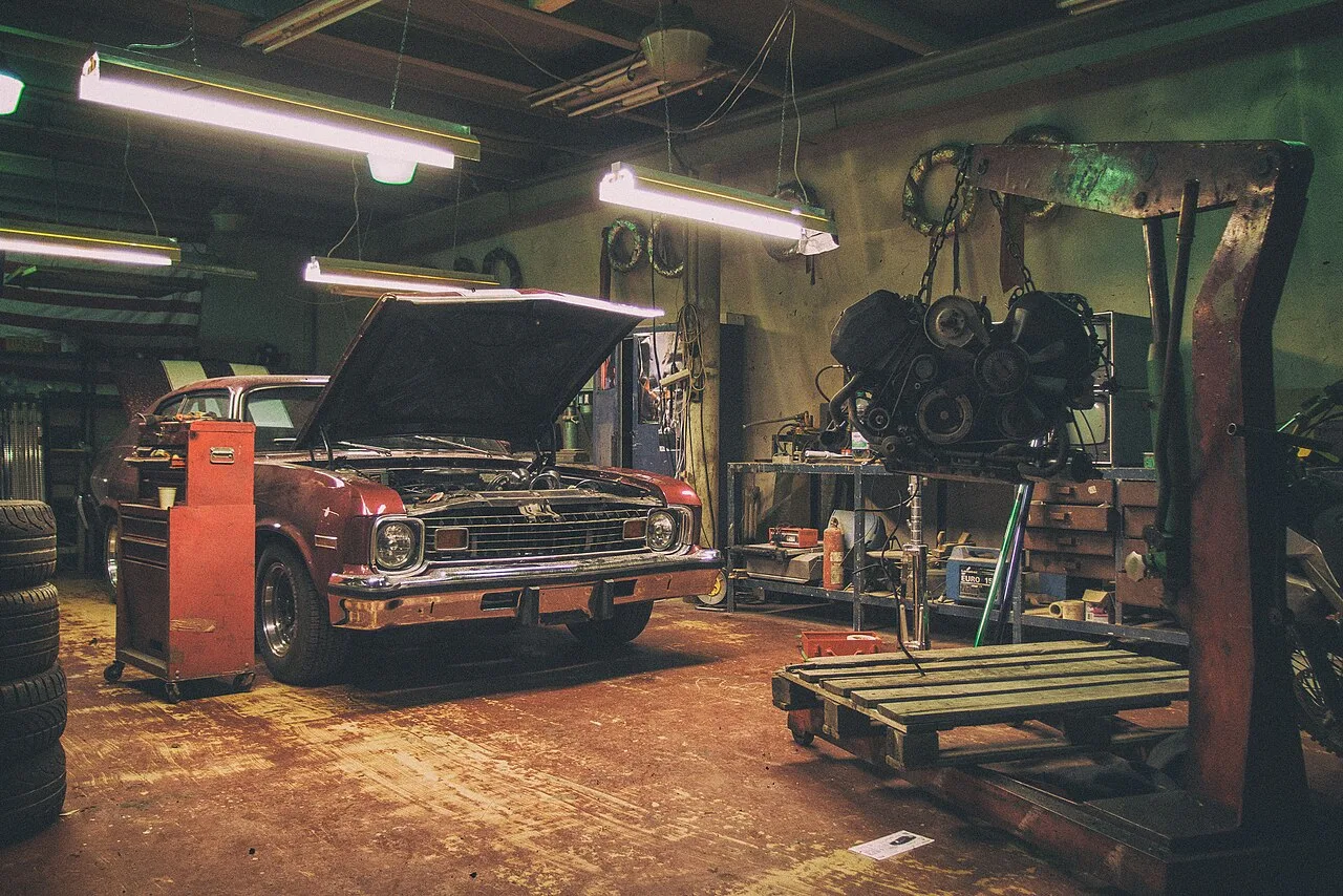 Vintage red car and detached engine in an automotive repair shop